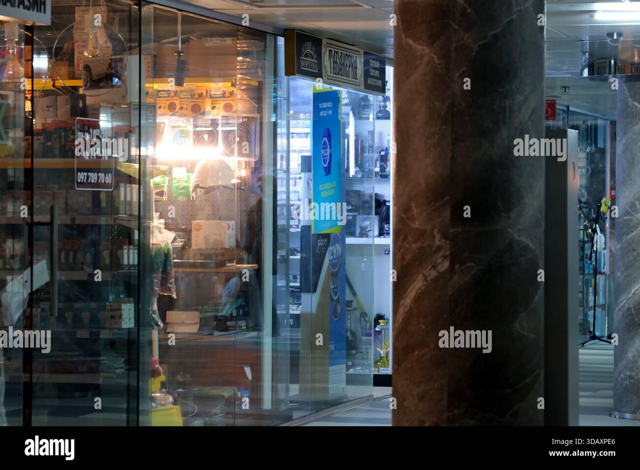 Le luci accese rivelano vari negozi allineati, mentre le ombre ballano nello spazio vivace. Kiev, Ucraina. 12 dicembre 2025. Foto Stock