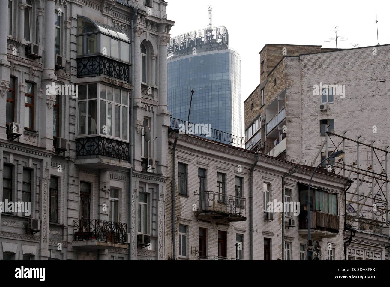 Vecchi edifici con dettagli intricati contrastano con un grattacielo elegante e torreggiante. Kiev, Ucraina. 12 dicembre 2025. Foto Stock