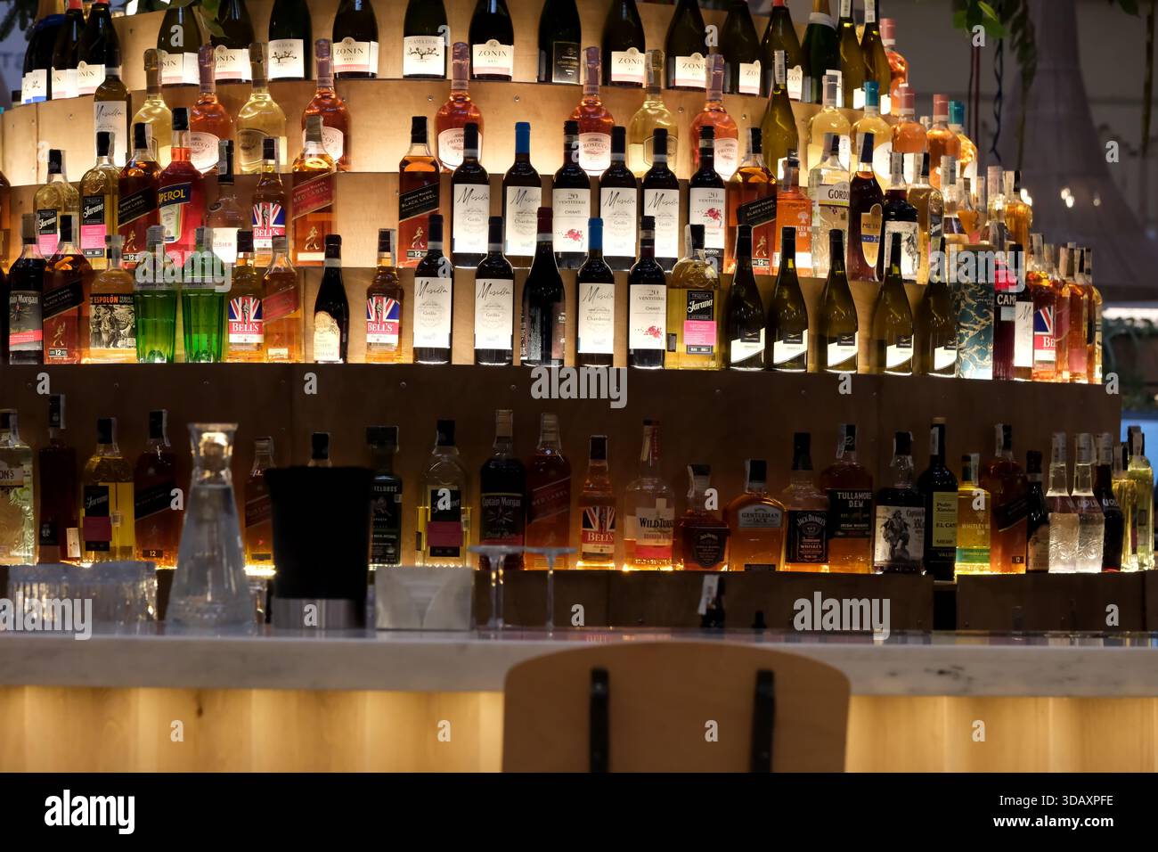 Bottiglie di vari liquori brillano in un bar circolare in un'atmosfera vivace. Kiev, Ucraina. 12 dicembre 2025. Foto Stock
