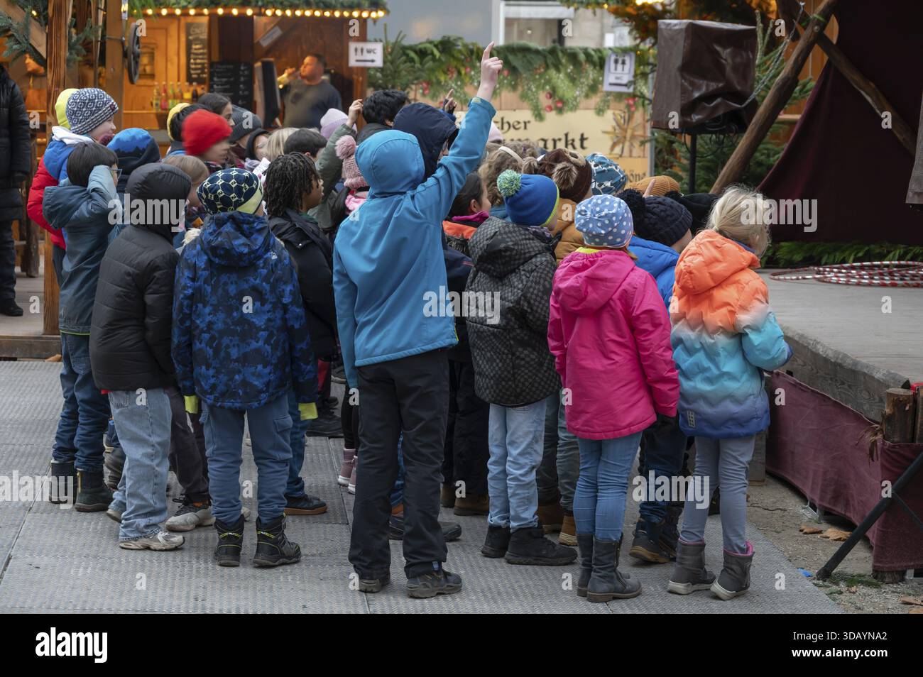 Un gruppo di bambini guarda un acrobato sul palco, il mercato di Natale Historischer am Neustaedter Church Square, Erlangen, Middle Franconia, Baviera, Germ Foto Stock