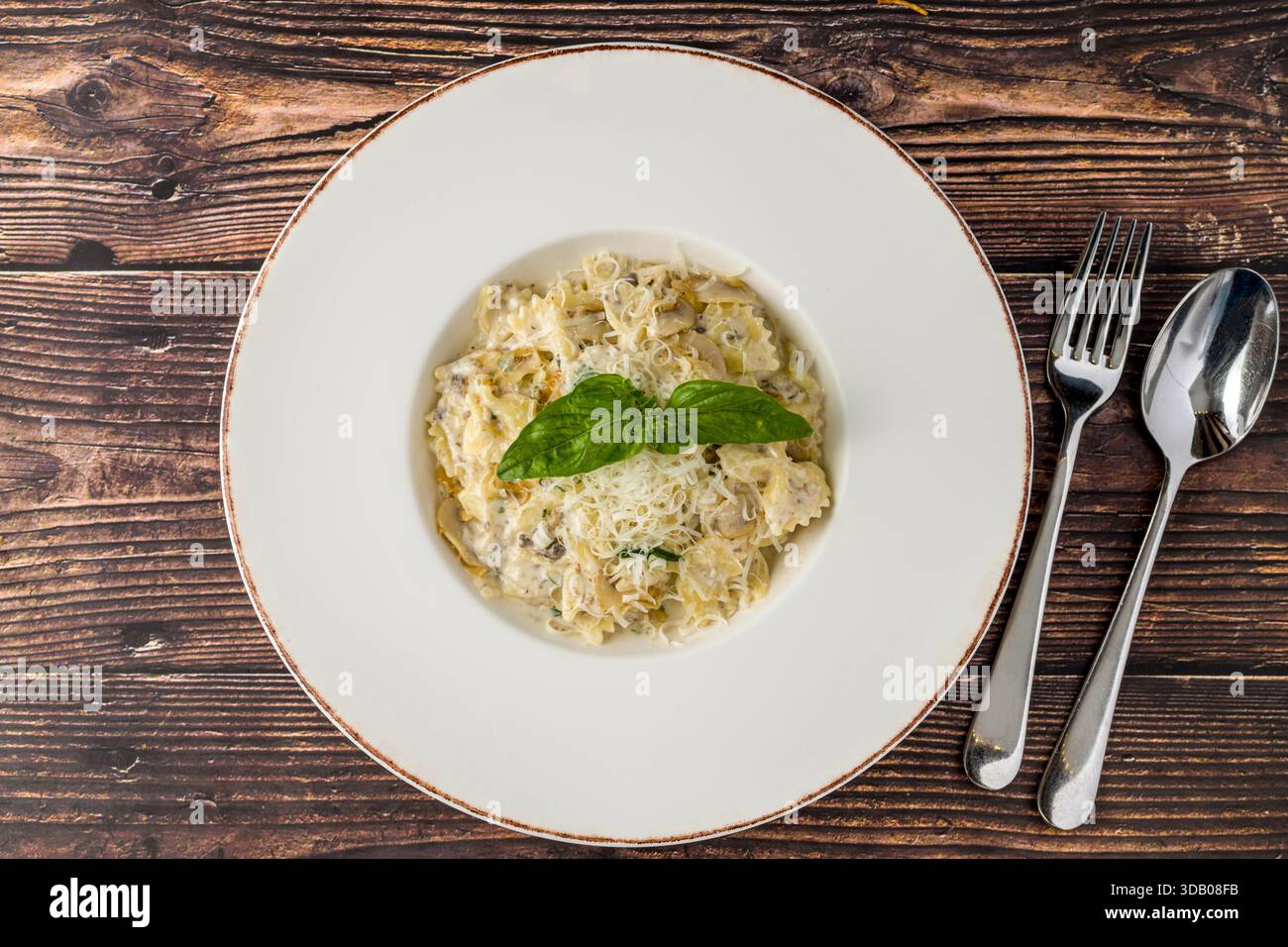 Pasta cremosa di funghi condita con parmigiano grattugiato e basilico fresco Foto Stock