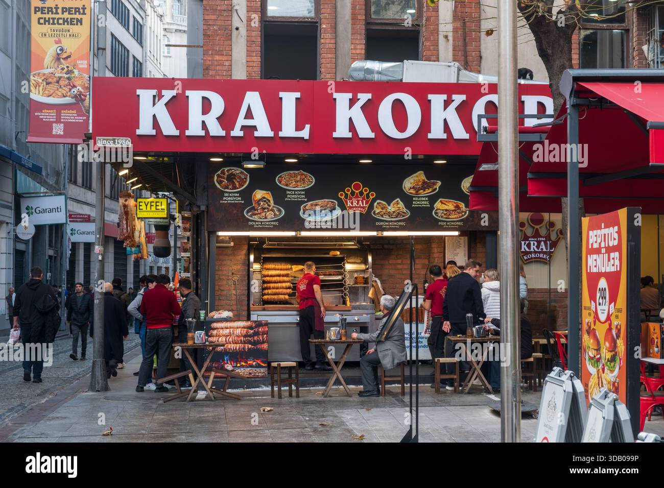 Famoso ristorante di Street food Kral Kokorej con clienti che mangiano cucina tradizionale turca e pedoni sulla strada trafficata di Eminönü Istanbul Turchia Foto Stock