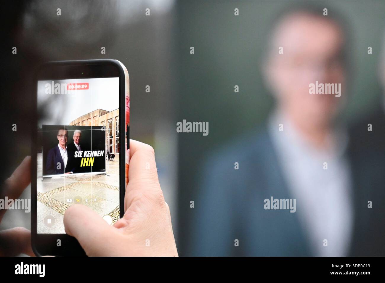 Ludwigsburg, Germania. 13 dicembre 2025. Una donna filma un poster di fronte al Forum am Schlosspark, dove Bündnis 90/Die Grünen Baden-Württemberg sta tenendo la sua conferenza del partito di stato. Il partito adotta il programma elettorale per le elezioni statali del 2026 ed elegge il suo comitato esecutivo statale, tra gli altri comitati di partito. Credito: Katharina Kausche/dpa/Alamy Live News Foto Stock