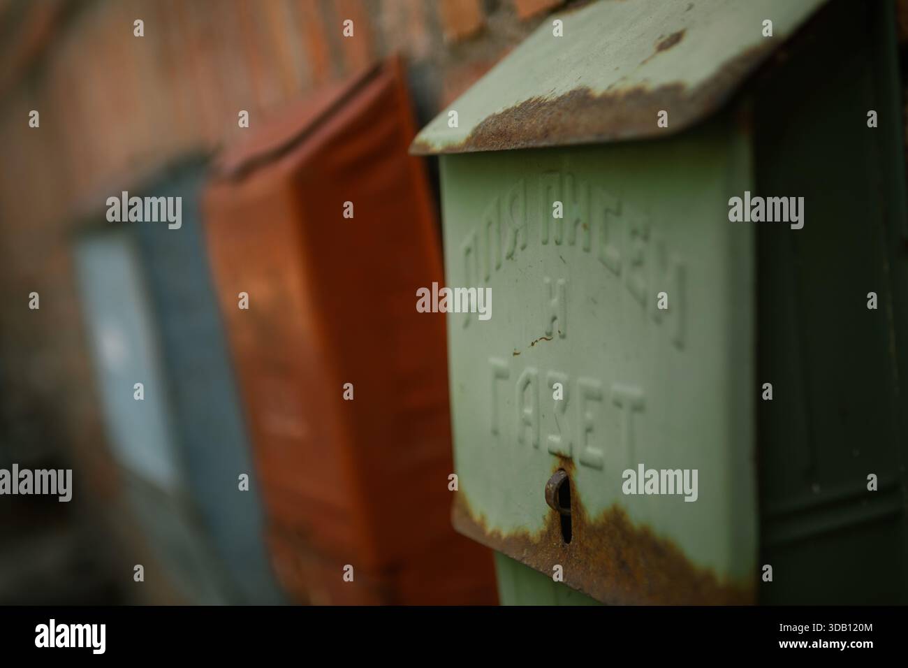 Vecchie cassette postali in metallo su una parete di mattoni, una russa "per lettere e giornali", mostrano una texture resistente agli agenti atmosferici e un fascino urbano rustico. Foto Stock