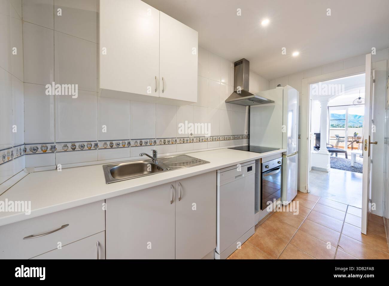 Interno di cucina bianca con elettrodomestici in acciaio inossidabile in una casa vacanza mediterranea Foto Stock