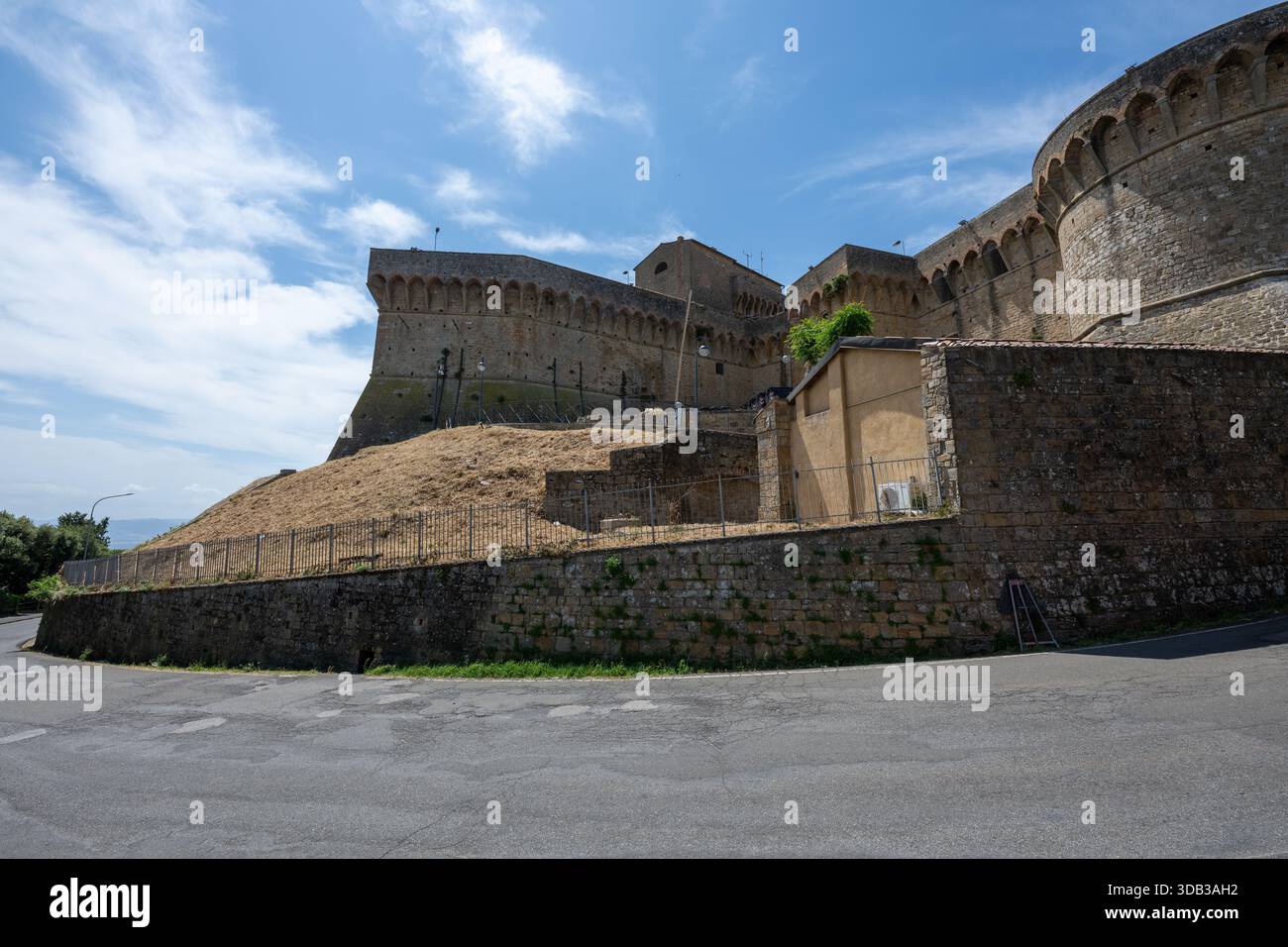 Bastioni in pietra nei pressi di porta a Selci, parte delle mura difensive medievali e di epoca medicea di Volterra sotto un cielo estivo. Foto Stock