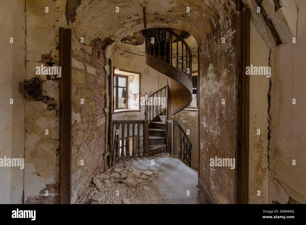 Scala a chiocciola in legno in un edificio abbandonato in rovina Foto Stock