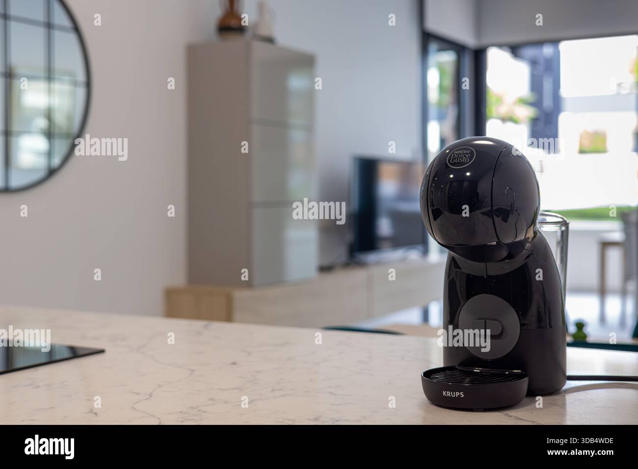 Primo piano della macchina per il caffè a capsule nere in un'elegante cucina con piano in marmo e unità TV Foto Stock