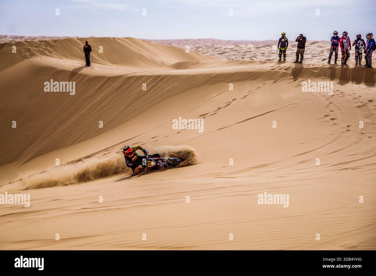 Fai un giro in bici sulle dune di sabbia durante la rally nel deserto con gli spettatori sul crinale delle dune Foto Stock