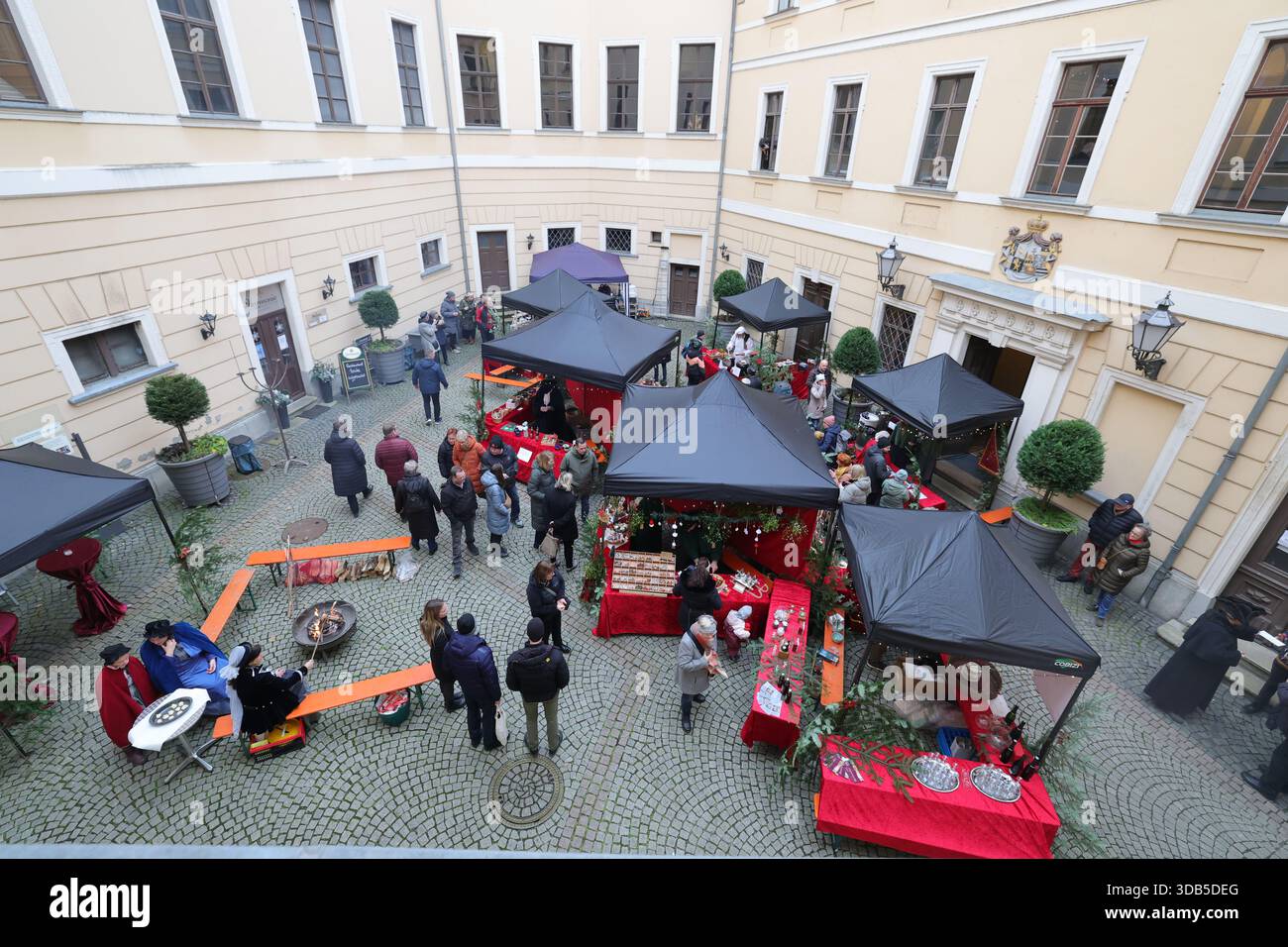 Greiz, Germania. 14 dicembre 2025. I visitatori si fermano presso le bancarelle nel cortile interno del Castello inferiore presso il "Natale dei principi romantici". I visitatori potranno vivere un viaggio natalizio indietro nel tempo, nel XVIII e XIX secolo, nelle sale storiche del Castello inferiore. Credito: Bodo Schackow/dpa/Alamy Live News Foto Stock