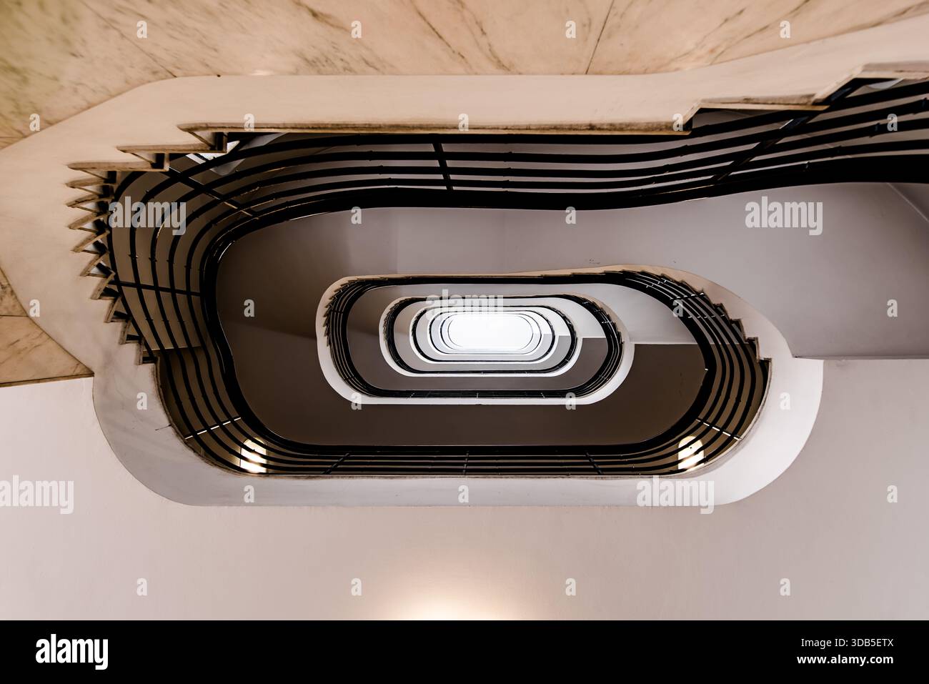 Scala a spirale ovale rivolta verso l'alto - interno simmetrico con ringhiere nere e lucernario centrale Foto Stock