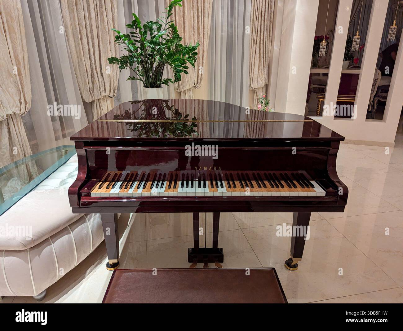 Kiev, Ucraina, 30 giugno 2025: Un pianoforte a coda si erge in uno splendido interno luminoso con alte finestre e pavimento in marmo lucido. Luce naturale soffusa rif Foto Stock