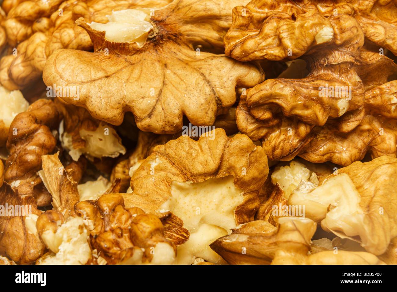 Metà dei chicchi di noce sono disposti insieme in una bancarella del mercato nel pomeriggio, mostrando le loro conchiglie dure e i pezzi interni. Foto Stock