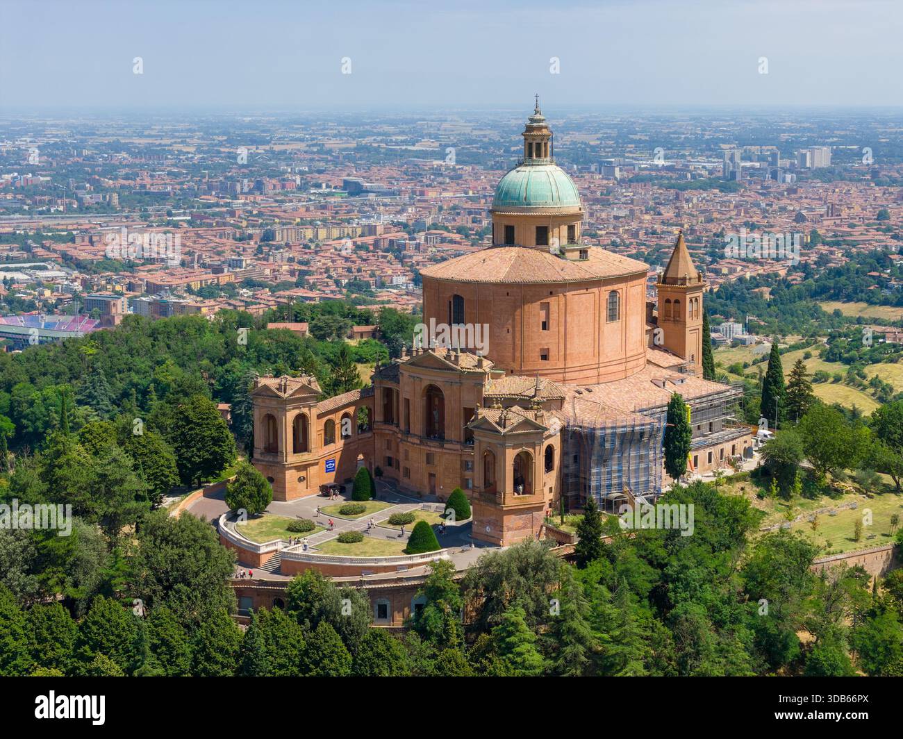 Santuario barocco in mattoni di nostra Signora di San Luca sulla collina del Monte della Guardia sopra Bologna, circondato da alberi e paesaggi urbani. Foto Stock