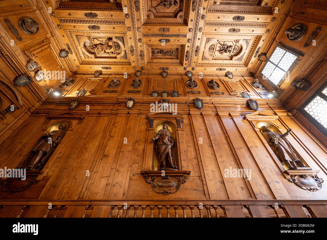 Bologna, Italia - 23 luglio 2025: Muraglia in legno intagliato e soffitto a cassettoni con statue e scudi araldici all'interno della Biblioteca Comunale Archiginnasio Foto Stock