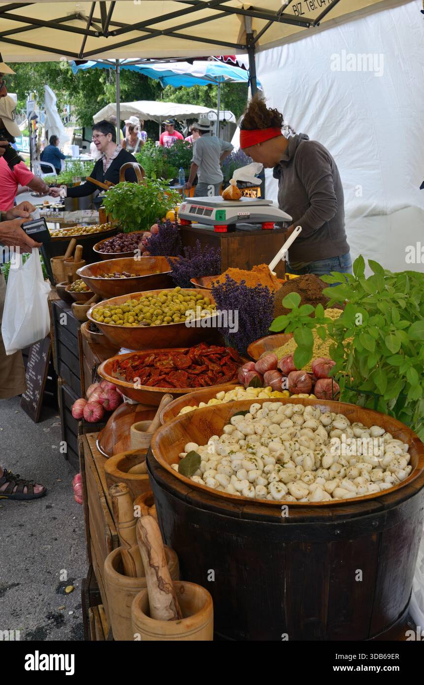 Ferrassieres, Francia - 6 luglio 2014: Aglio, olive, spezie e pomodori secchi marinati e freschi in grandi vasi di legno al mercato rurale. Provenzale Foto Stock