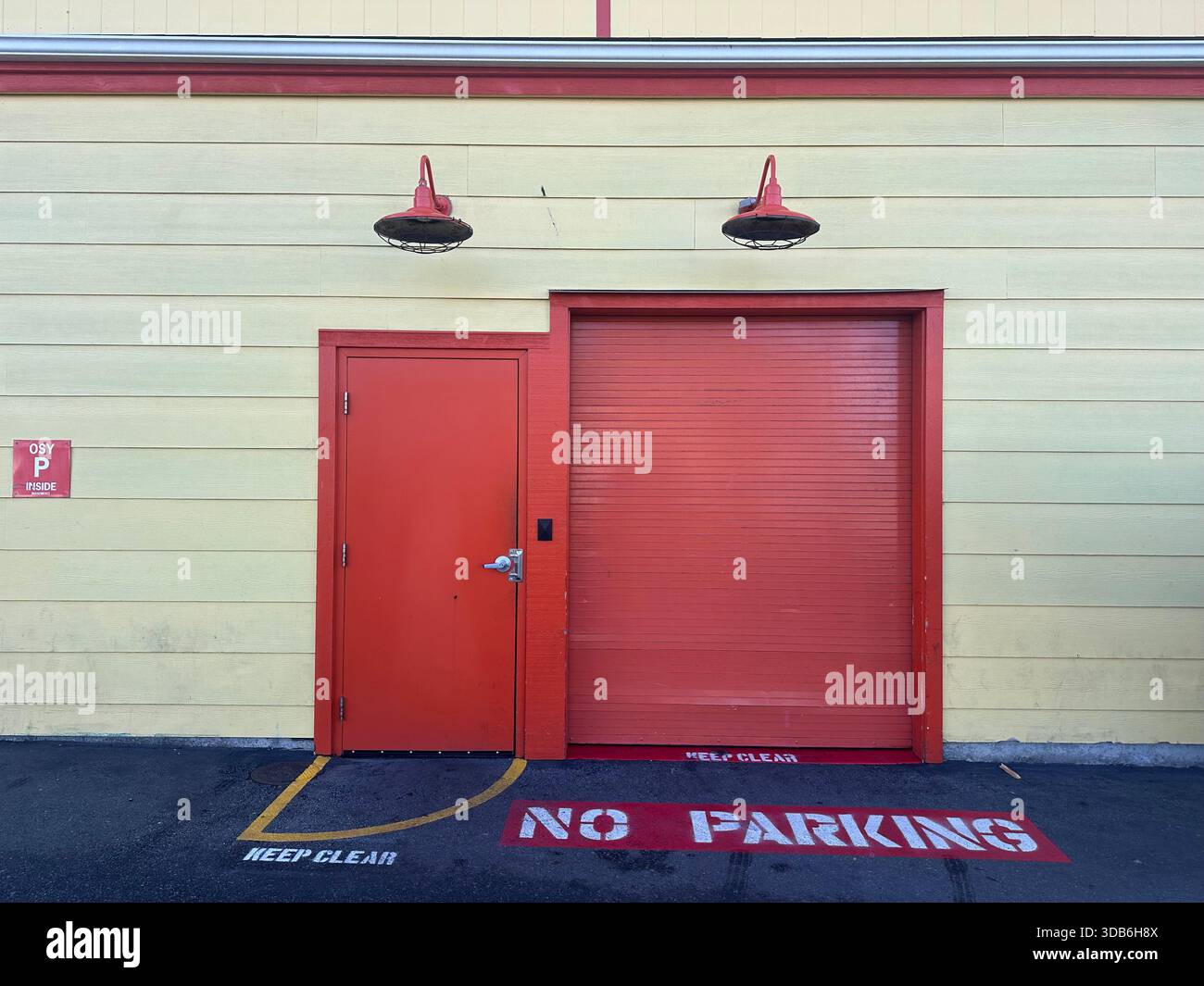 Nessun cartello di parcheggio verniciato a terra davanti alla porta industriale rossa - Immagine stock catturata con smartphone