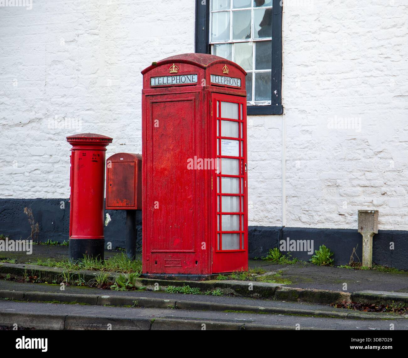Tradizionale cabina telefonica rossa britannica accanto a una cassetta postale rossa in una strada tranquilla con un edificio dipinto di bianco sullo sfondo di Calne Wiltshire UK Foto Stock