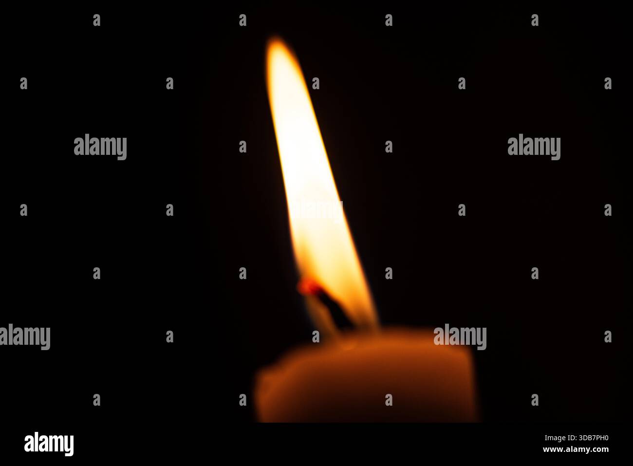 Una foto macro dettagliata di una fiamma di una candela, che cattura il caldo bagliore, il delicato sfarfallio e la texture atmosferica della cera ardente. Perfetto per i temi Foto Stock