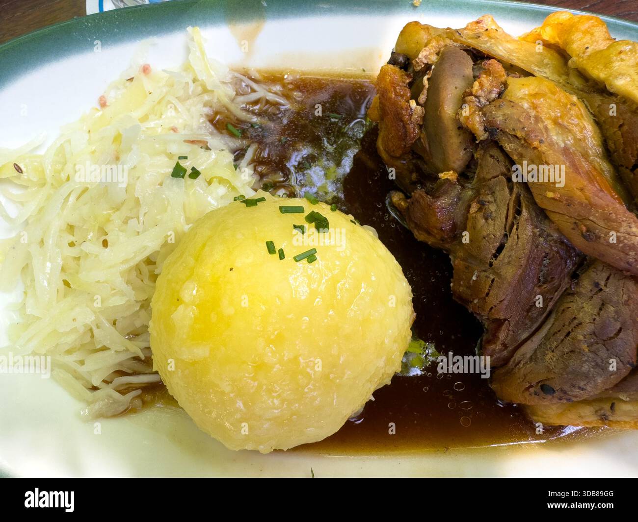 Schweinehaxe tedesco con buccia croccante, un grande gnocco di patate, salsa e crauti Foto Stock
