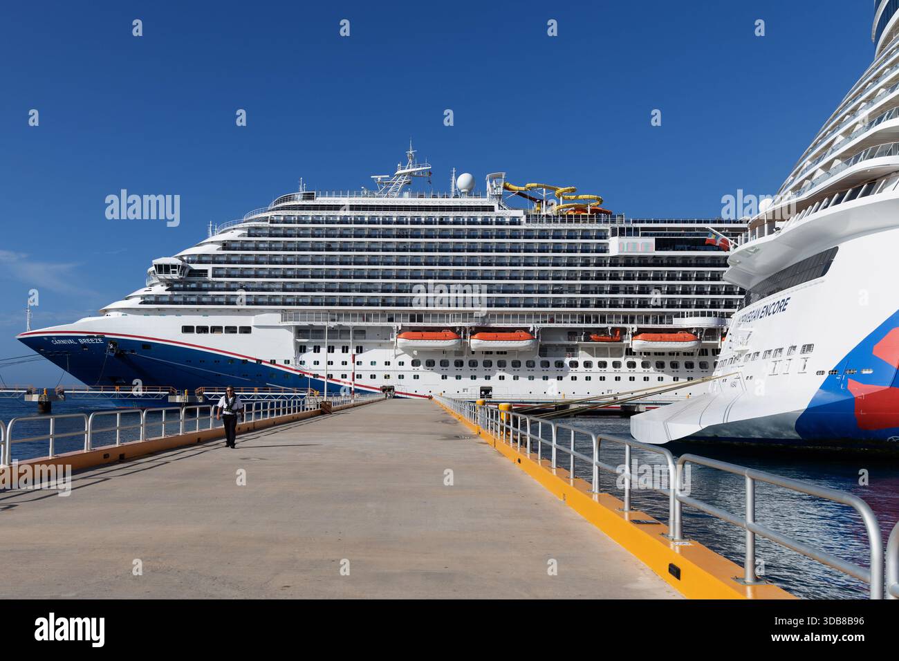 Navi da crociera attraccate fianco a fianco al molo di Cozumel, Messico, con passeggeri che sbarcano sotto il cielo azzurro dei Caraibi. Foto Stock