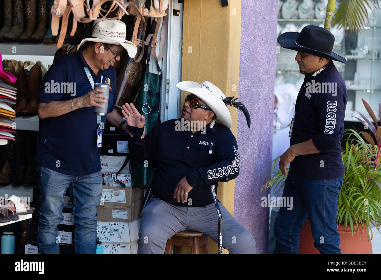 I venditori locali chiacchierano all'esterno di un negozio di articoli in pelle vicino al molo delle navi da crociera di Cozumel, Messico. Foto Stock