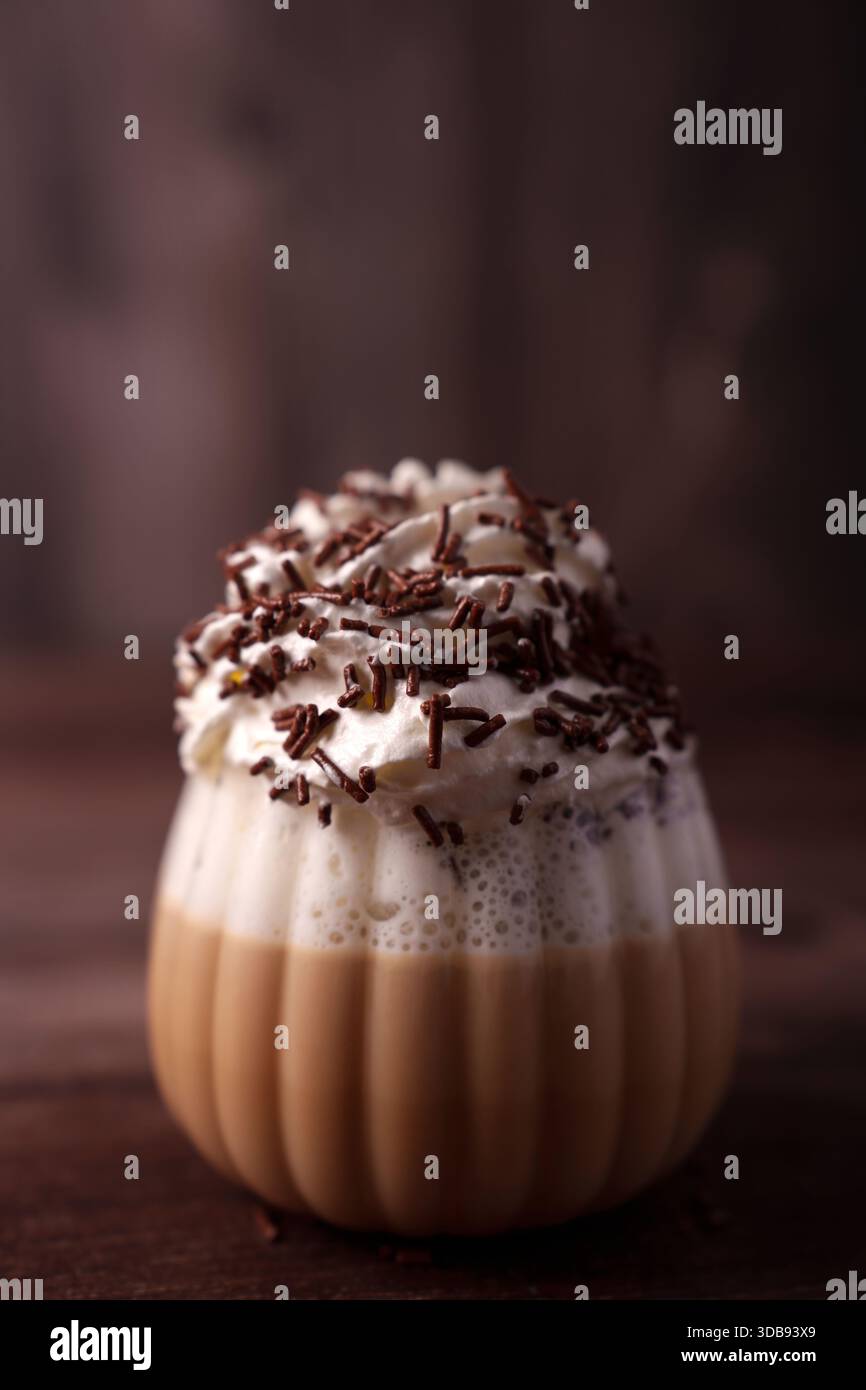 deliziosa bevanda da dessert in vetro a costine con cremosa copertura montata e ricche spruzzette di cioccolato in un ambiente caldo e accogliente, saporito, decadente e gustoso Foto Stock