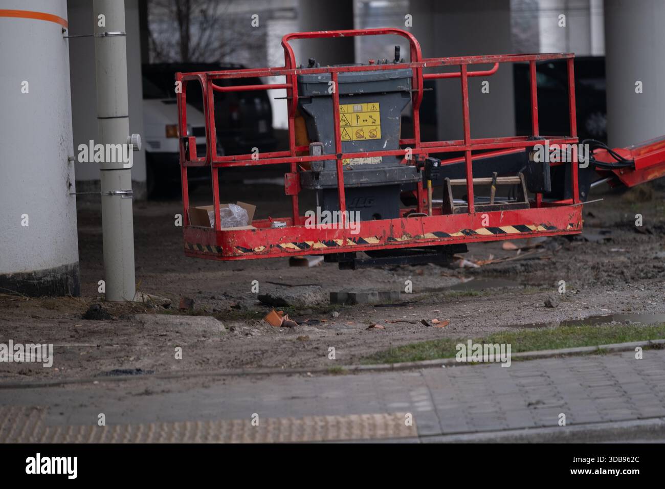 Piattaforma di sollevamento mobile rossa in piedi a terra vicino a un edificio in fase di ristrutturazione. L'immagine mostra le attrezzature utilizzate per lavori di facciata, mainten Foto Stock