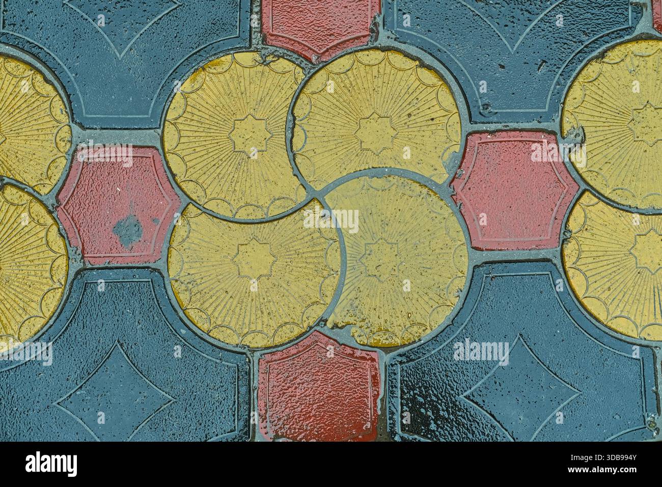 Piastrelle geometriche bagnate sui marciapiedi urbani dopo la pioggia. Superficie in pietra decorativa con mosaico ripetuto, adatta per sfondo astratto, Foto Stock