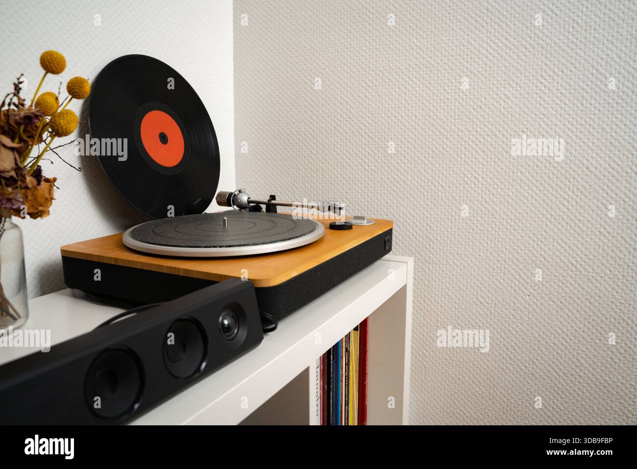 Disco in vinile appoggiato a una parete accanto a un giradischi in un semplice interno. Configurazione musicale di tutti i giorni con uno stile minimalista. Concetto di musica, audio, Foto Stock