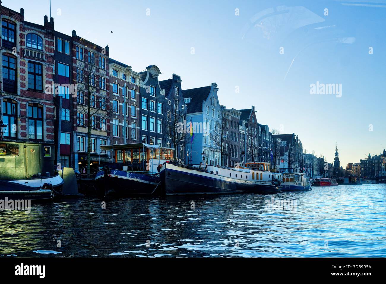 Le case galleggianti galleggiano dolcemente lungo i canali di Amsterdam mentre il sole tramonta, gettando riflessi sull'acqua, Amsterdam, Paesi Bassi, Europa Foto Stock