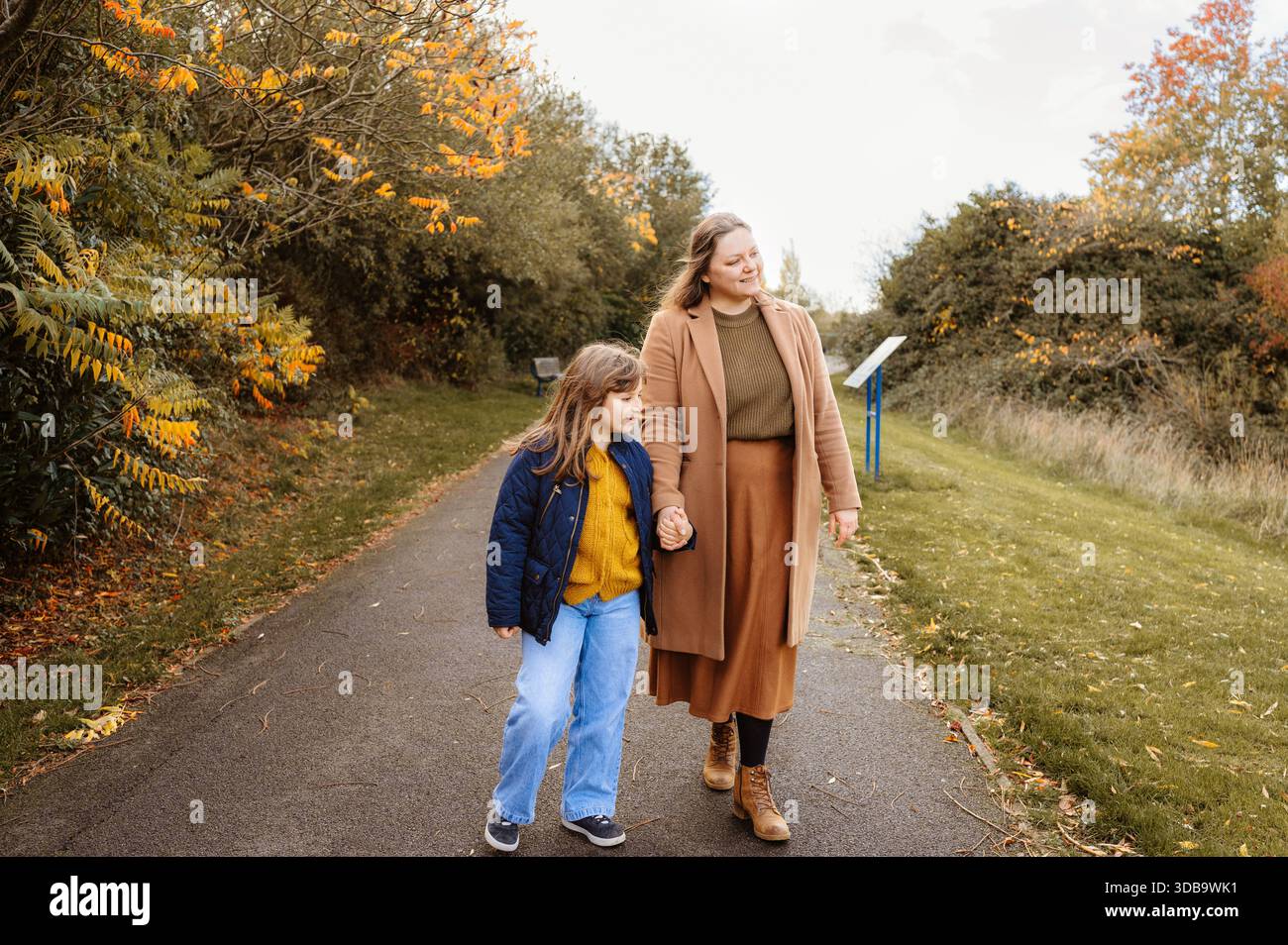 Madre e figlia camminano insieme su un sentiero autunnale nel parco Foto Stock
