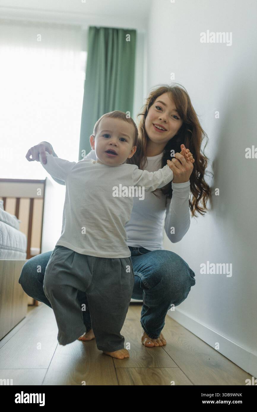 Il bambino impara a camminare con il supporto a casa Foto Stock