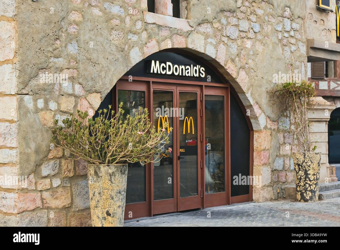 Ingresso del ristorante McDonald's in un edificio in pietra in ambiente urbano. Dubai, Emirati Arabi Uniti. Negozi di fast food internazionali e scena urbana. Foto Stock