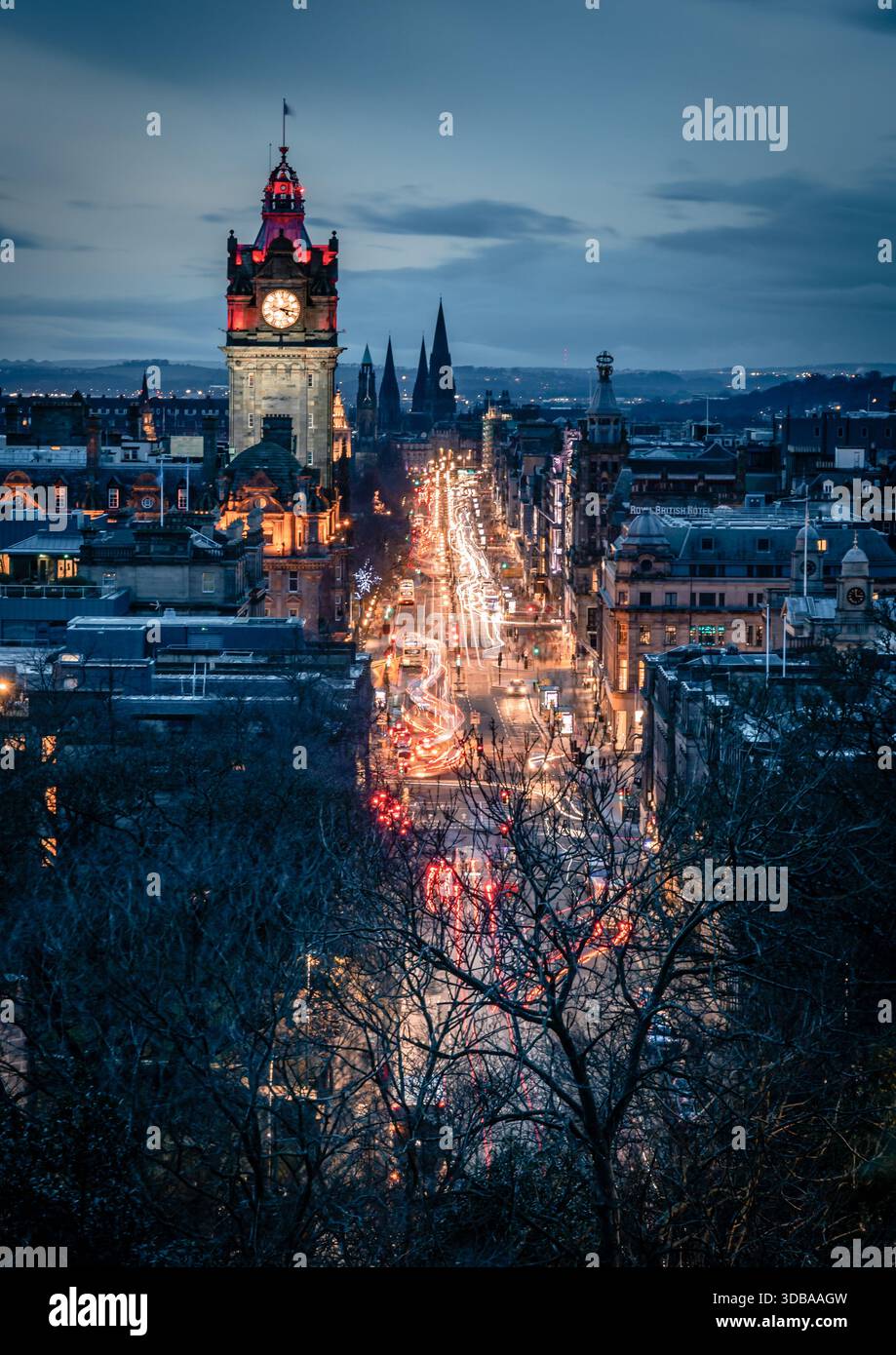 Il centro di Edimburgo al crepuscolo, visto da Calton Hill, presenta sentieri al semaforo di Princes Street e la torre dell'orologio del Balmoral Hotel Foto Stock
