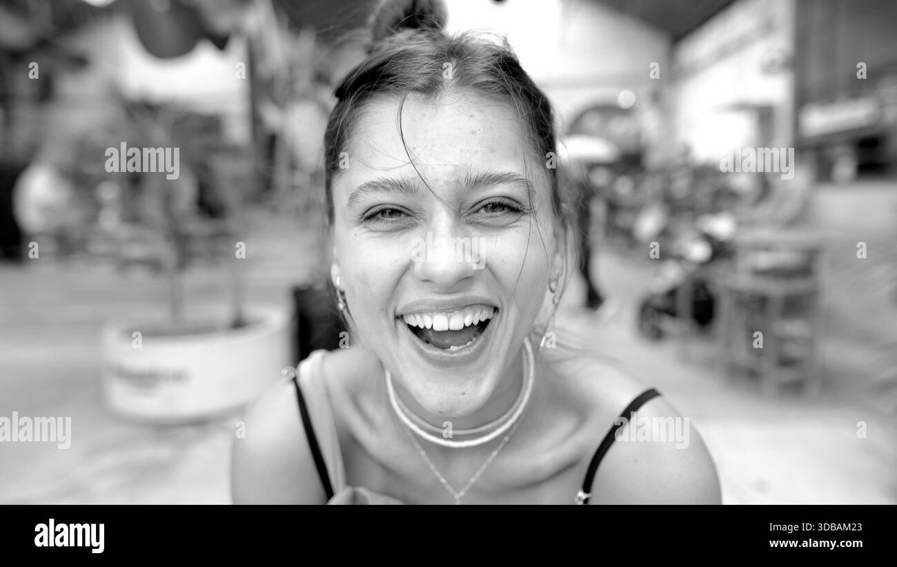 Una donna allegra ride gioiosamente in mezzo a una vivace scena di mercato, irradia pura felicità ed energia illimitata || modello rilasciato Foto Stock