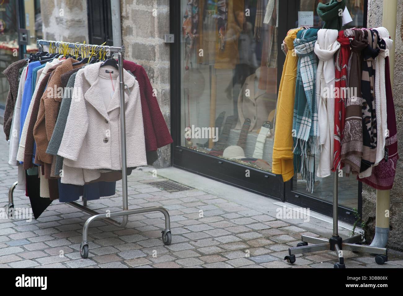 Scaffali di abbigliamento con cappotti, maglioni e sciarpe esposti all'esterno di una boutique a Nantes, Francia Foto Stock