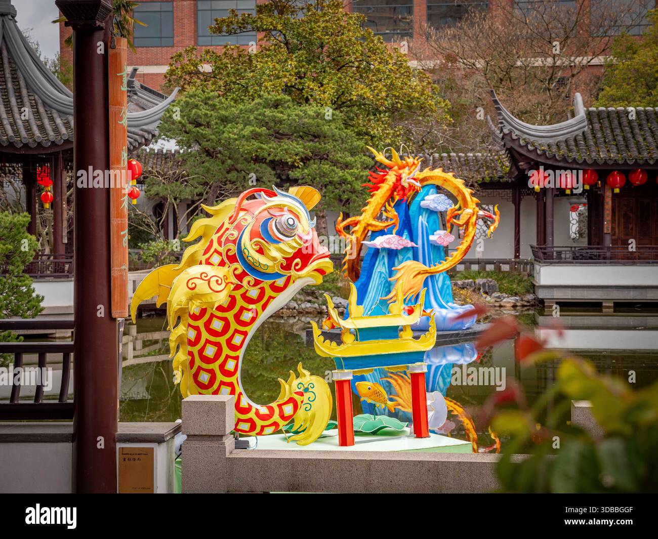 Vista delle vivaci statue di drago e pesci koi che si riflettono nelle acque dello stagno, con la tradizionale architettura cinese sullo sfondo, Portland, o. Foto Stock