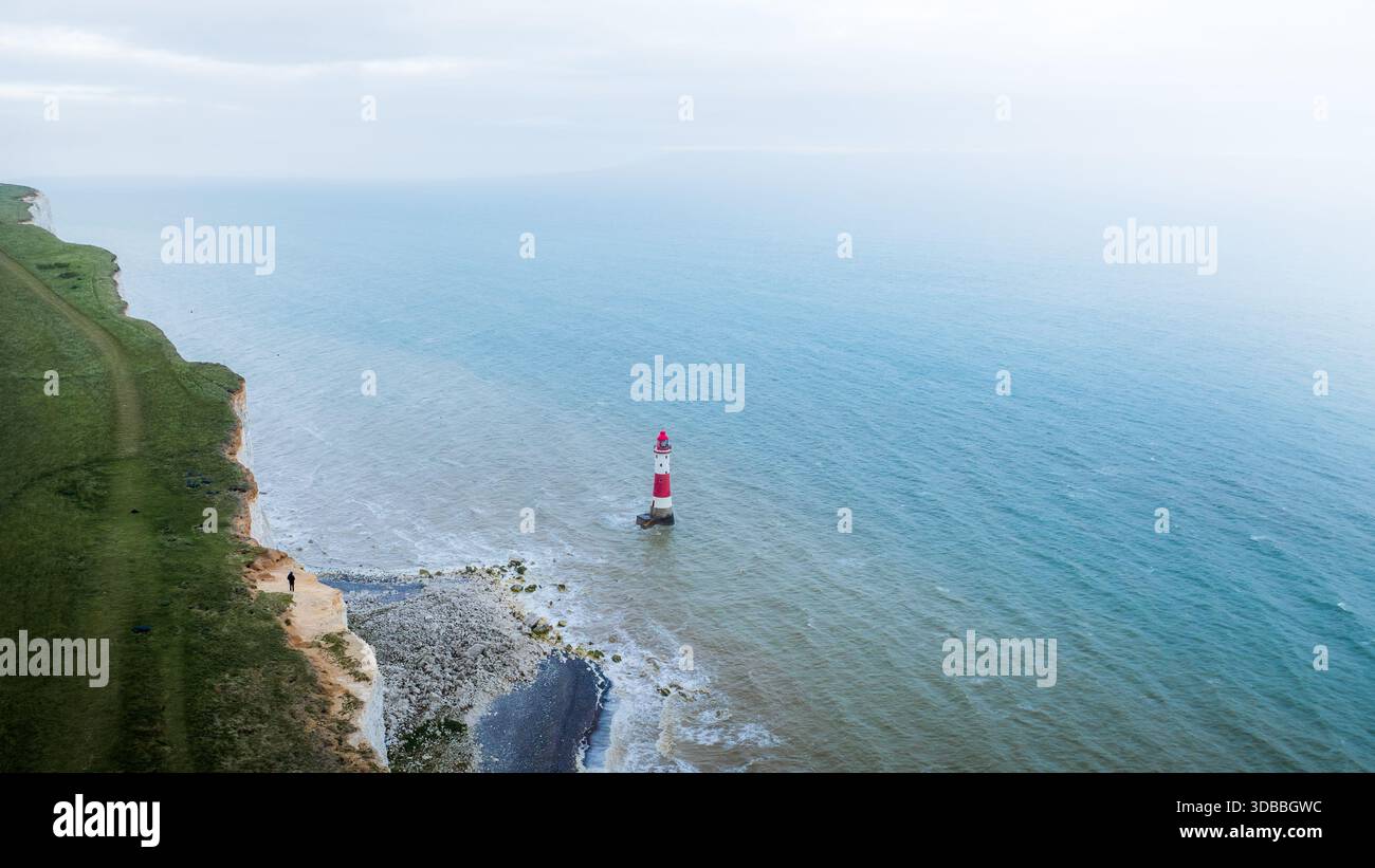 Veduta aerea di un faro rosso e bianco che si erge in piedi con fermezza contro le onde che si infrangono ai piedi delle scogliere di gesso, Eastbourne, United K Foto Stock
