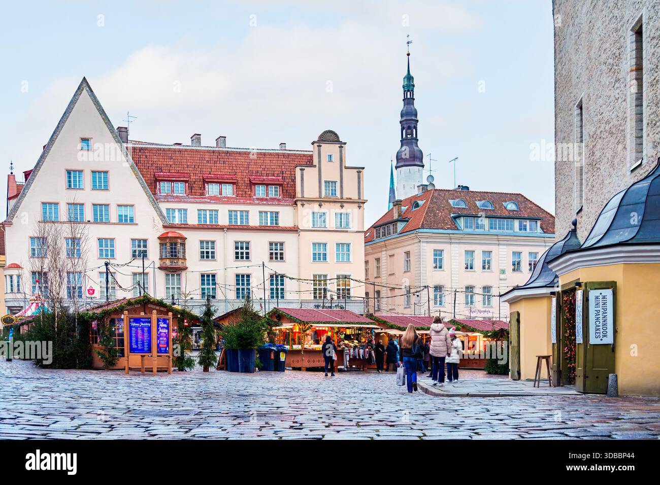 Tallinn, Estonia - 3 dicembre 2025: Le bancarelle del mercatino di Natale riempiono i piatti di Raekoja, con edifici storici e visitatori che creano una vivace scena dell'Avvento Foto Stock