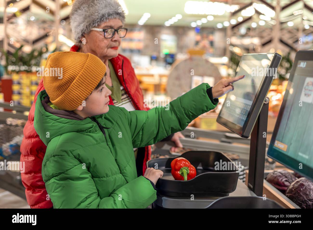 Young Boy assiste sua nonna con la tecnologia Digital Self Service durante il negozio di alimentari. supporto familiare, alfabetizzazione tecnologica, invecchiamento attivo e vigile Foto Stock