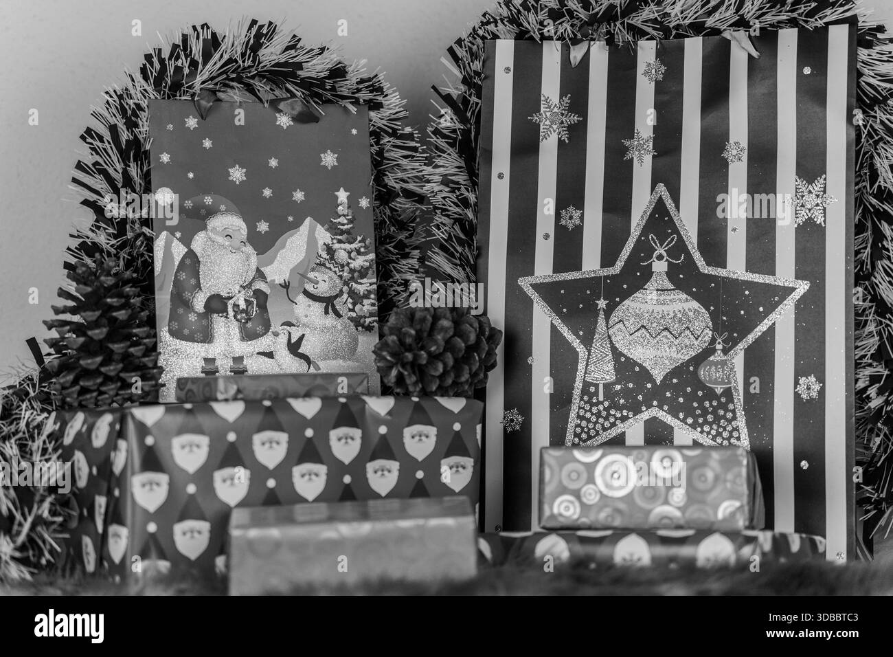 Un'immagine in bianco e nero di una selezione di regali di Natale con avvolgimento natalizio Foto Stock