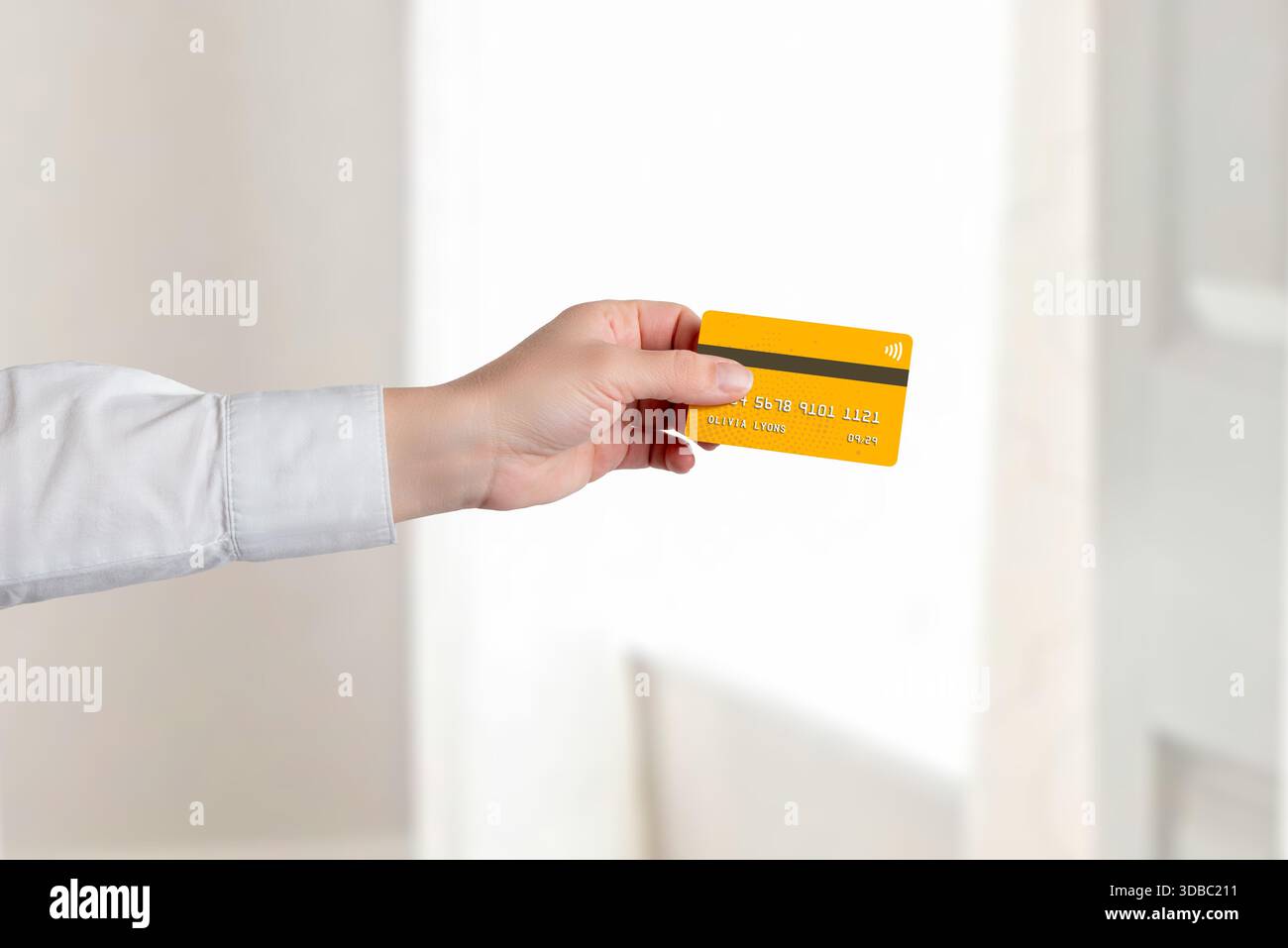 Mano con carta di credito contactless su sfondo luminoso, che rappresenta i moderni concetti bancari, dei pagamenti senza contanti e della tecnologia finanziaria Foto Stock