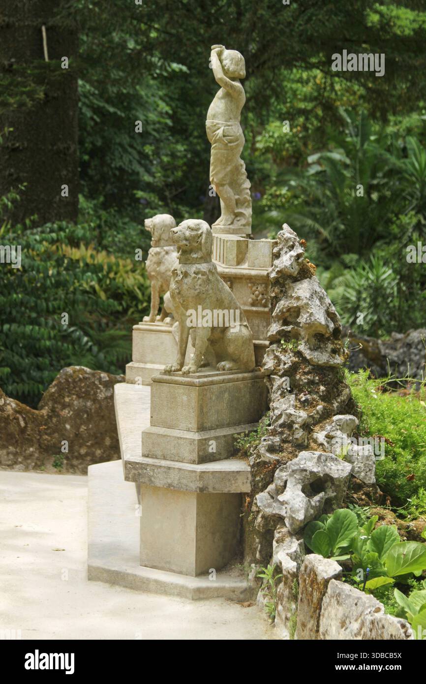 Sintra, Portogallo - 18 giugno 2025: Panchina in marmo mostra le figure di una ragazza e due cani nel Parco di Regaleira, circondato da una vegetazione vivace e da una vegetazione naturale Foto Stock