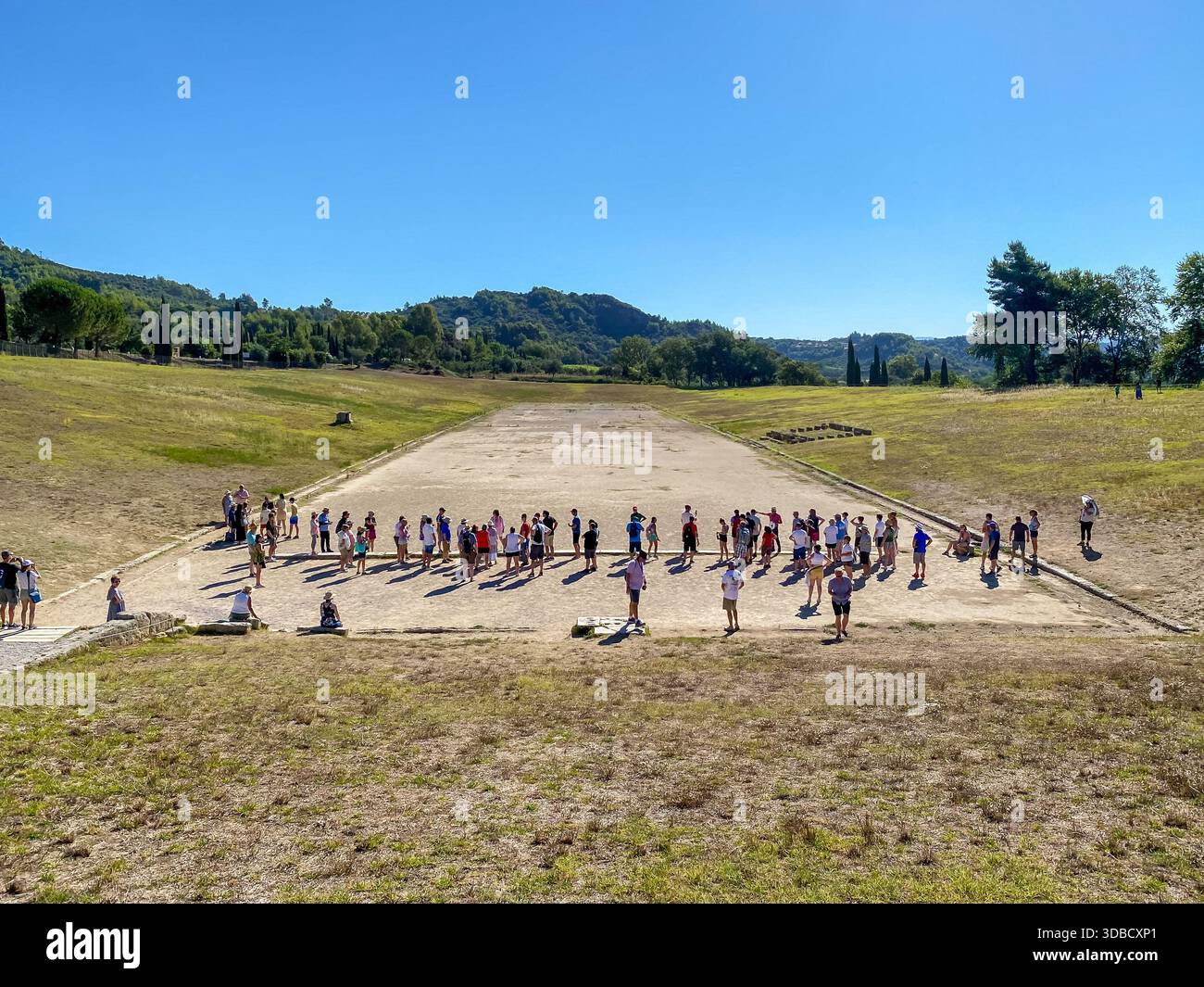 I turisti si riuniscono alla linea di partenza dell'Antico Stadio Olimpico di Olimpia, in Grecia, per imparare a conoscere le prime competizioni atletiche. Foto Stock