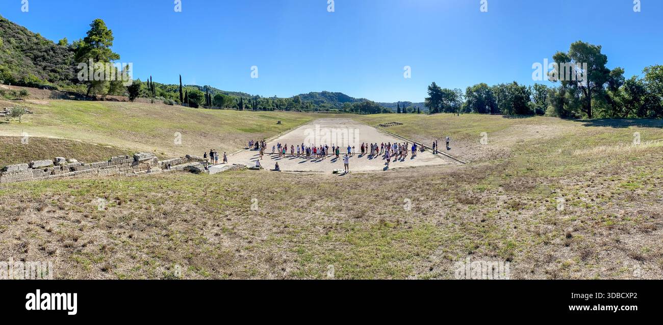 I turisti si riuniscono alla linea di partenza dell'Antico Stadio Olimpico di Olimpia, in Grecia, per imparare a conoscere le prime competizioni atletiche. Foto Stock