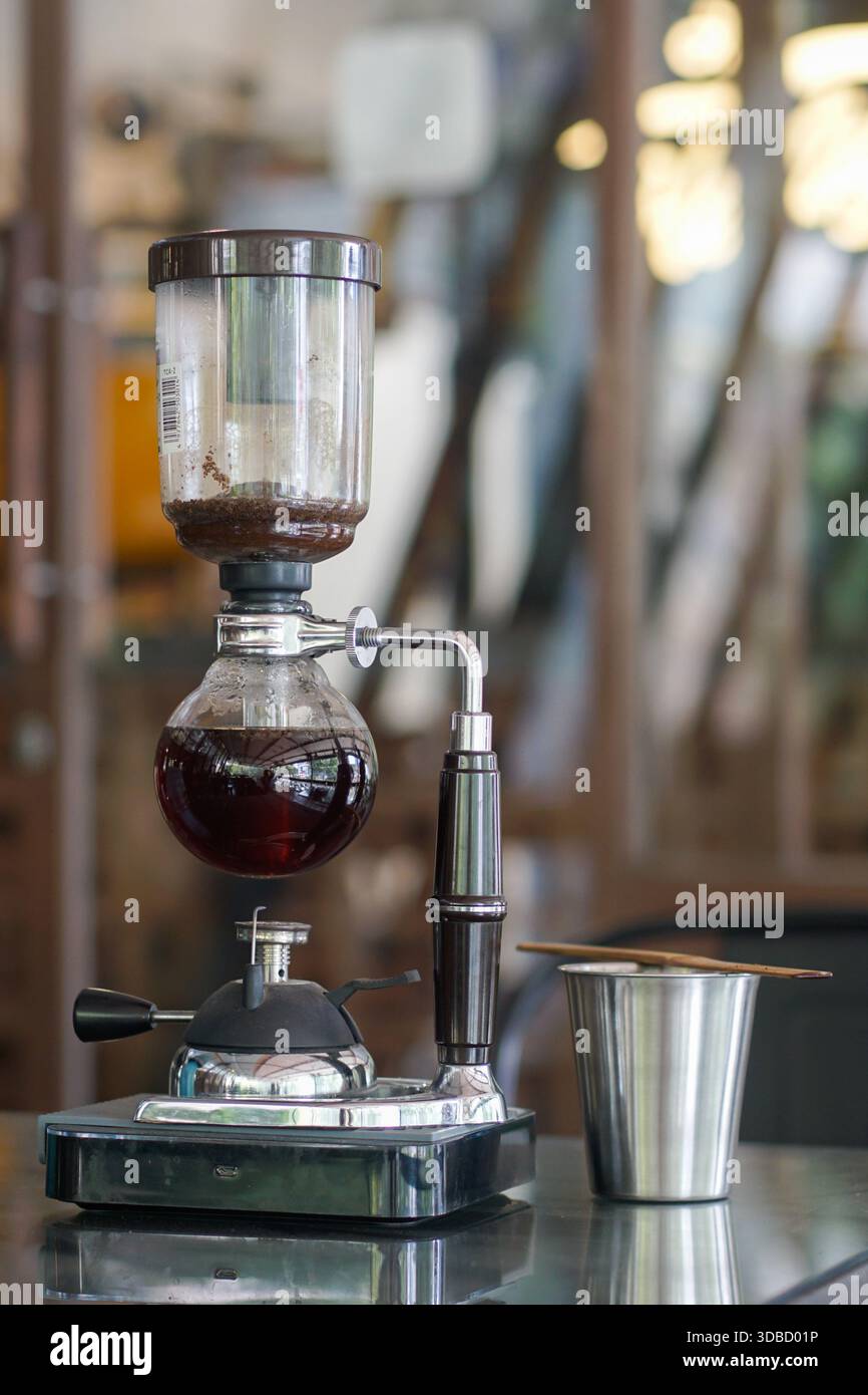 Preparazione manuale del caffè con sifone, tazza in ceramica e bicchiere sul tavolo, concetto di caffè speciale Foto Stock