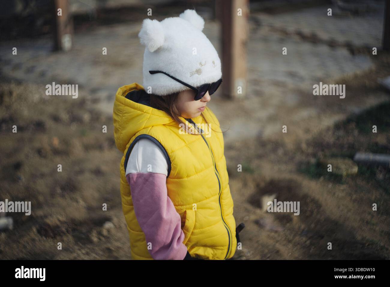 Il bambino che indossa il giubbotto luminoso cammina all'aperto pacificamente, il bambino che indossa il giallo esplora la tranquilla scena del parco Foto Stock