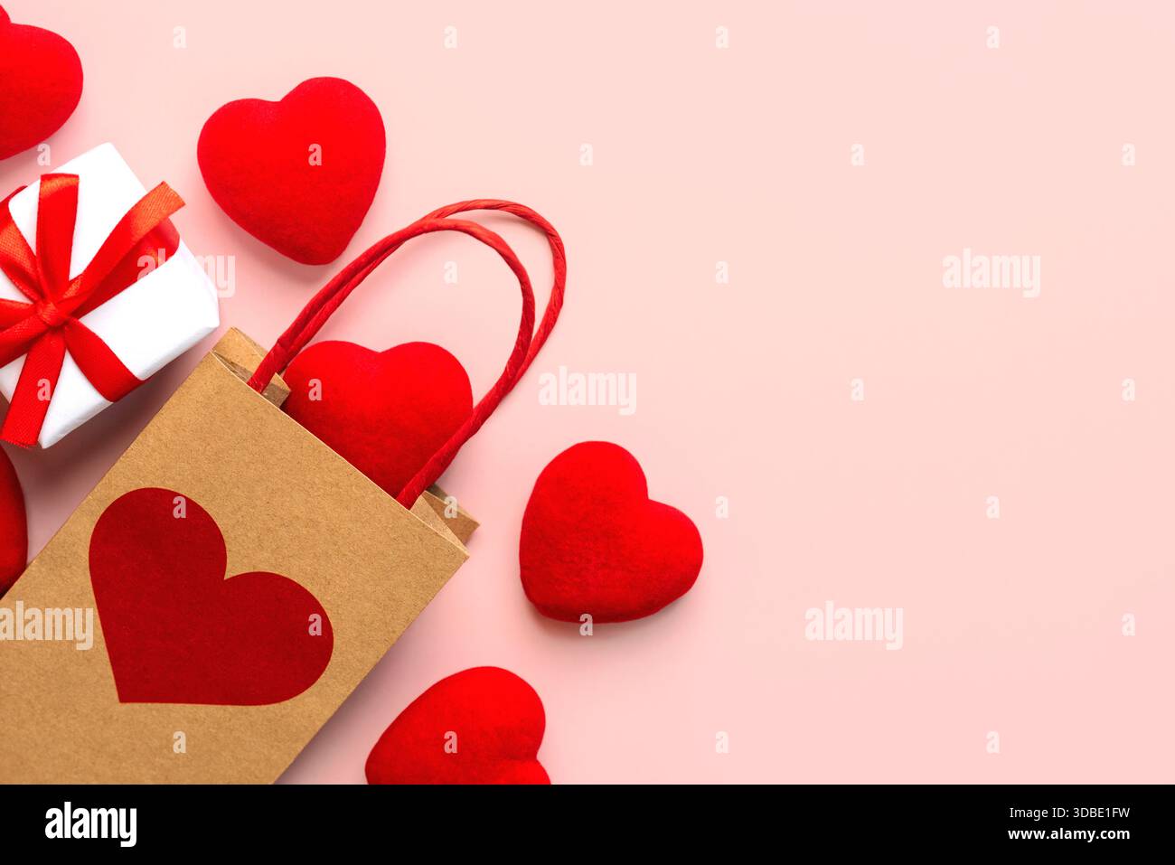 Vista dall'alto della shopping bag con cuore rosso, cuori rossi e spazio per testo su sfondo rosa. Concetto di San Valentino Foto Stock