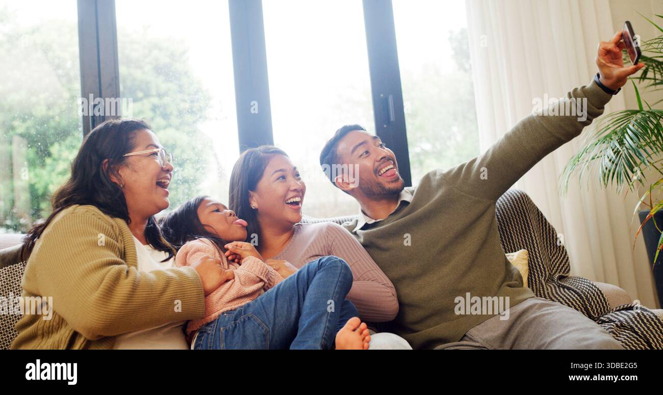 Casa, nonna e genitori con bambini, selfie e incollaggio in salotto, felice e memoria sul sito Web. Ridendo, nonno e gente con una ragazza dentro Foto Stock